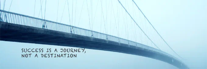En hængebro i tåge med teksten “Success is a journey, not a destination”: Succes er at gøre, hvad man vil, når man vil, med hvem man vil.